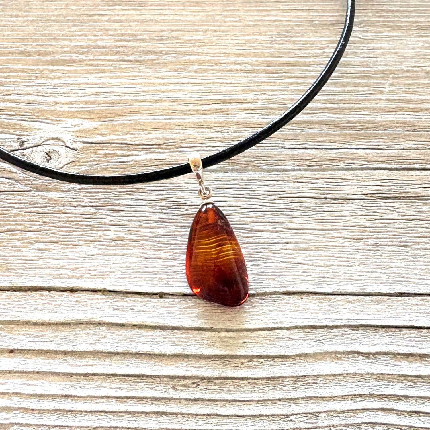 Necklace with a teardrop-shaped amber pendant on a wooden surface