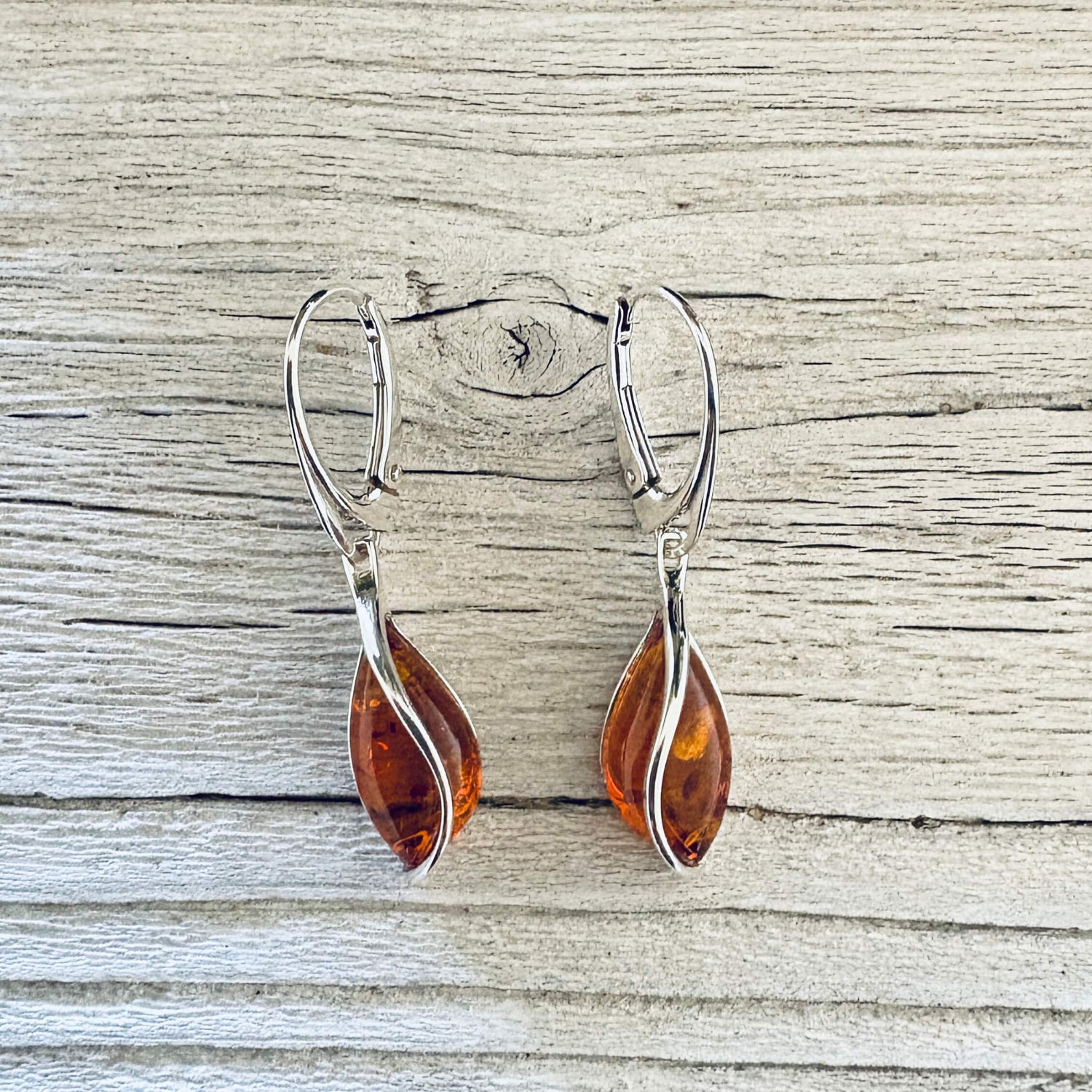 Close up translucent cognac Baltic amber drops embraced by graceful sterling silver curves.