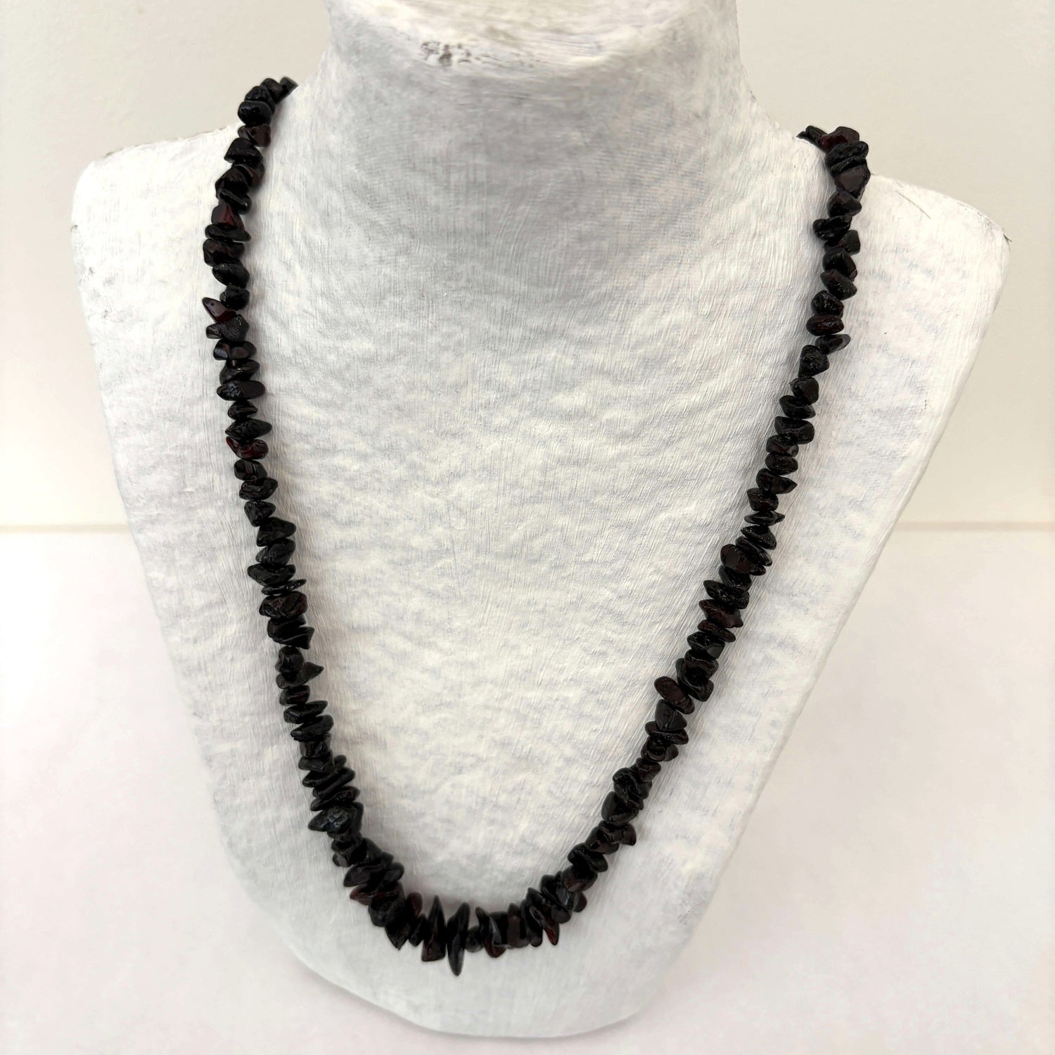 Dark cherry beaded amber necklace on a mannequin bust against a white background