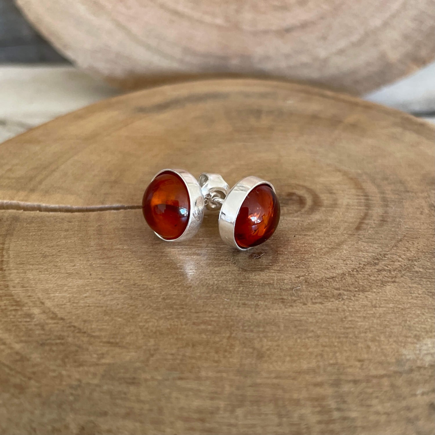 Round silver earrings with amber stones on a wooden surface