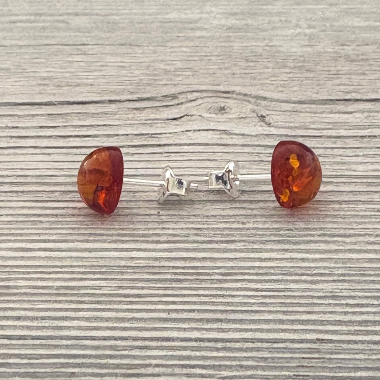 Pair of amber stud earrings on a wooden surface