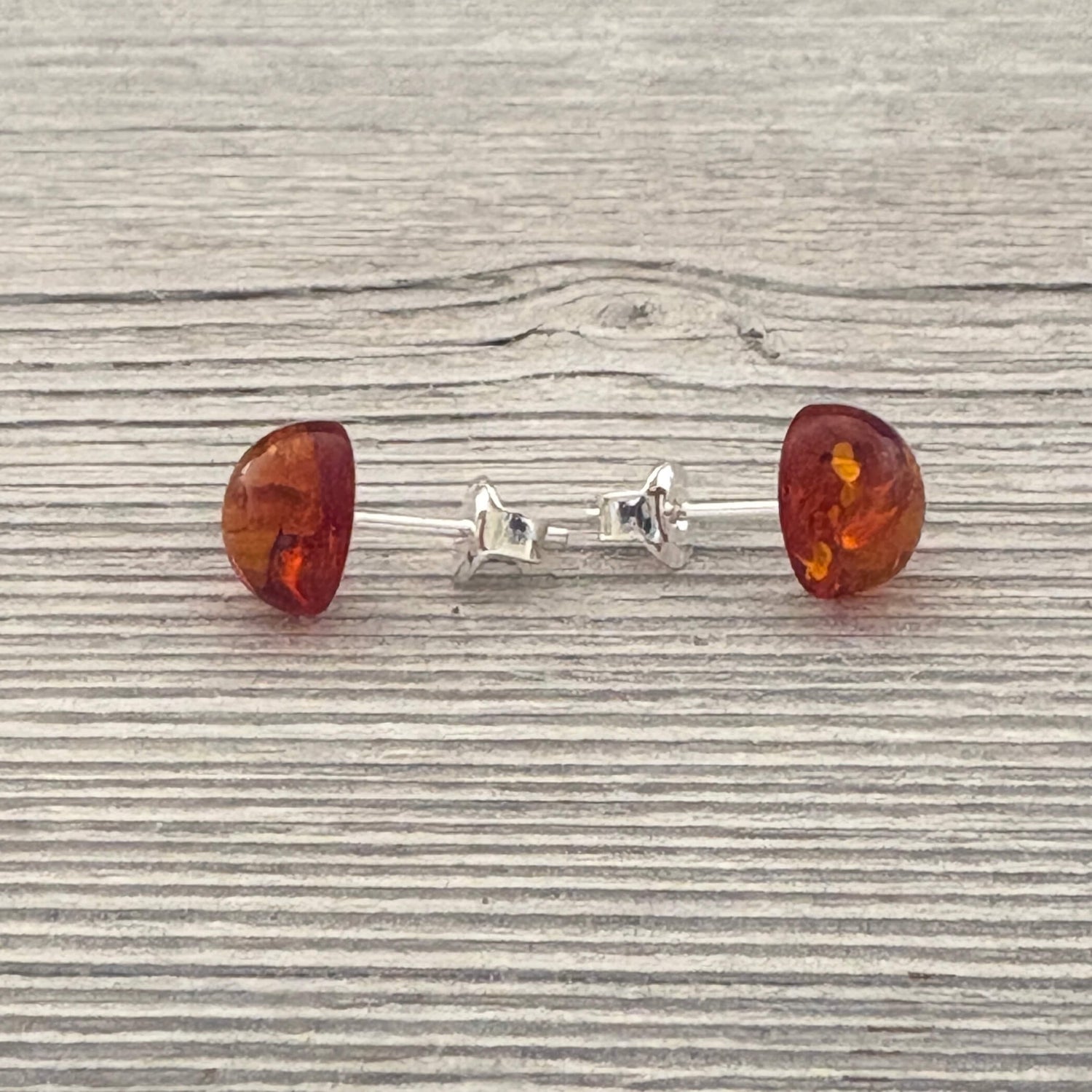 Pair of amber stud earrings on a wooden surface