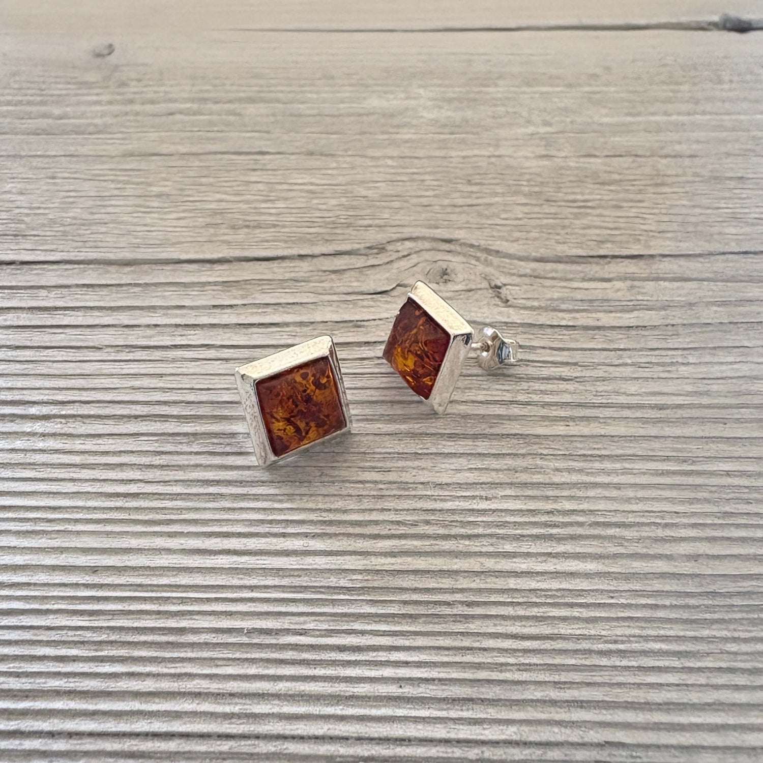 Square amber stud earrings on a wooden surface