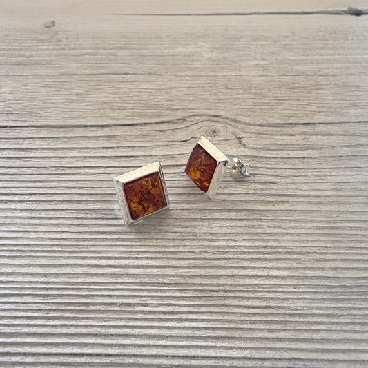 Square amber stud earrings on a wooden surface