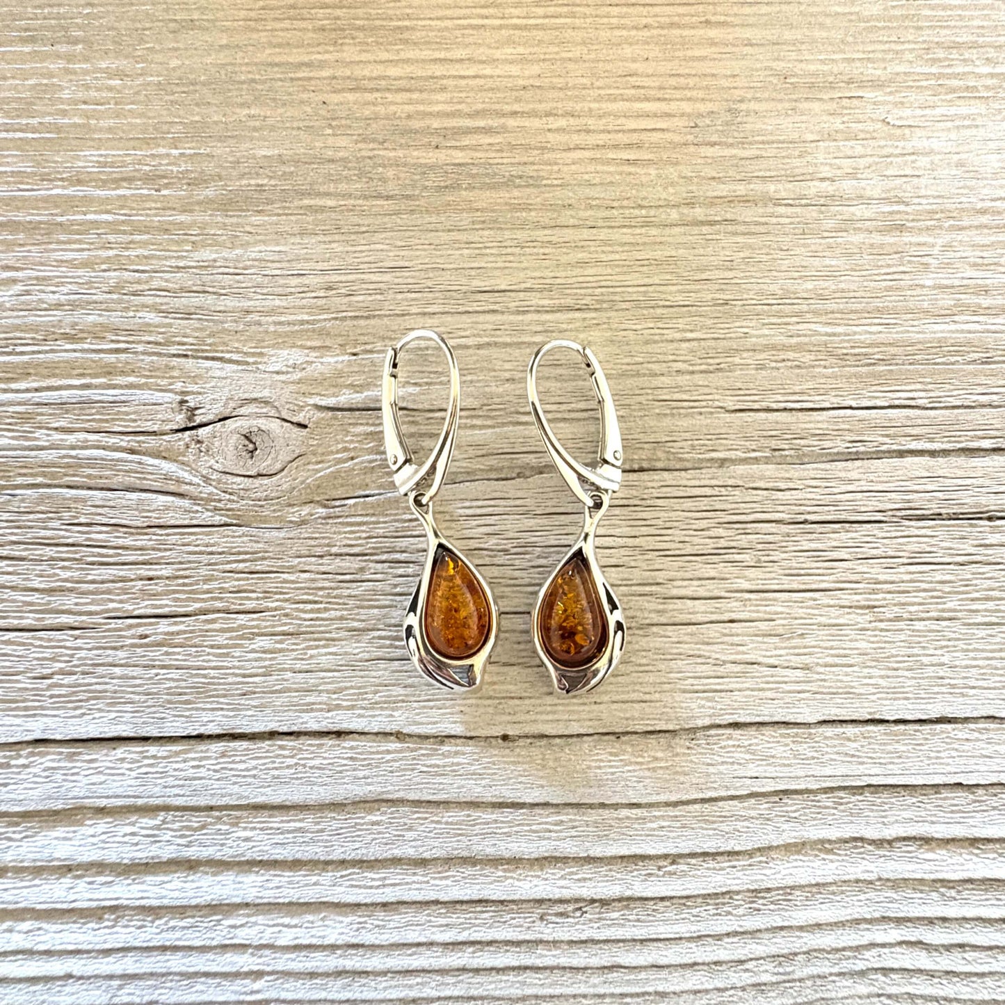 Pair of cognac amber drop earrings featuring polished silver teardrop settings and secure leverback closures.