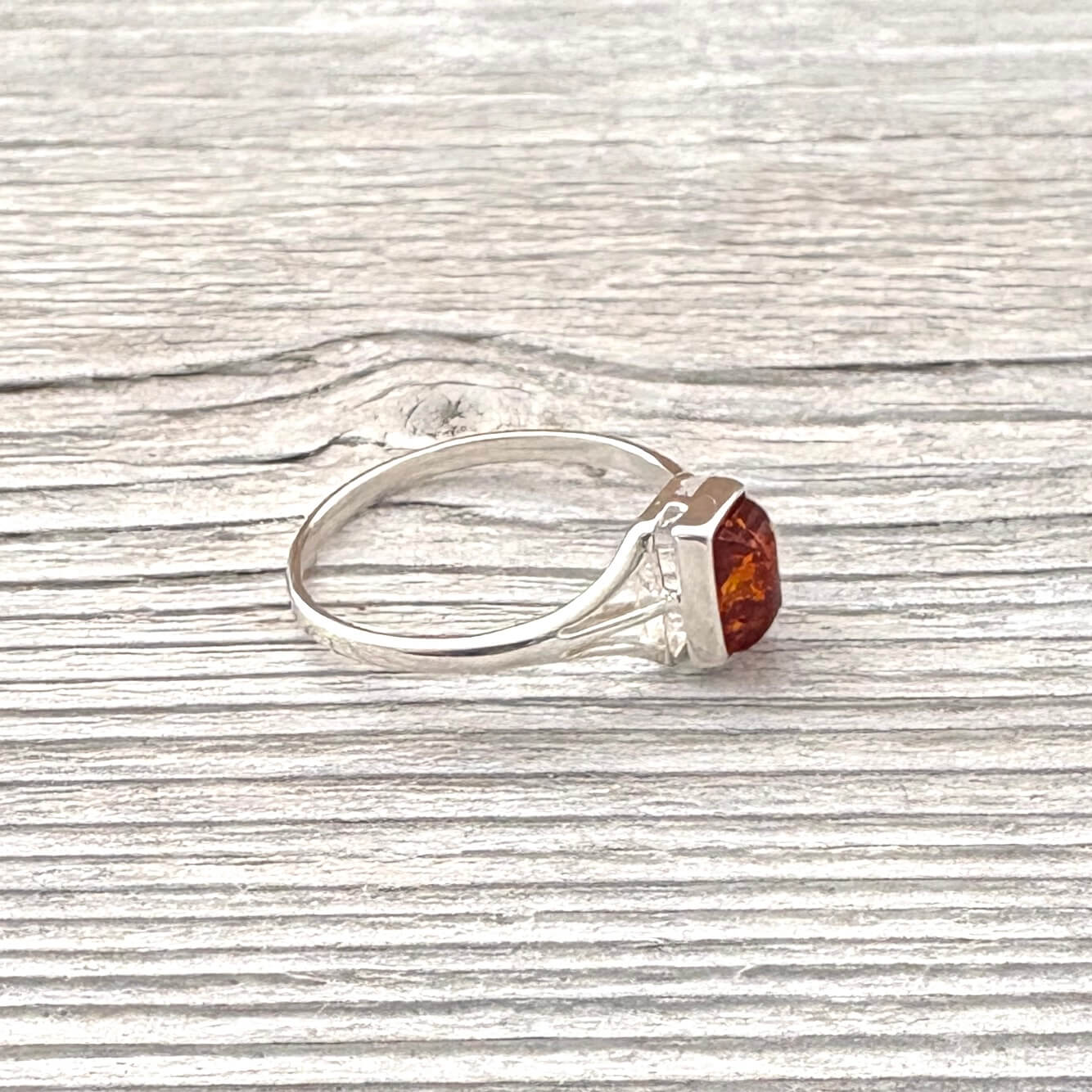 Silver ring with a cognac amber gemstone on a wooden surface