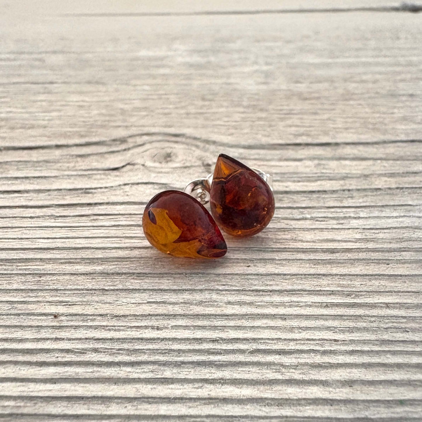 Teardrop shaped amber earrings on a wooden surface