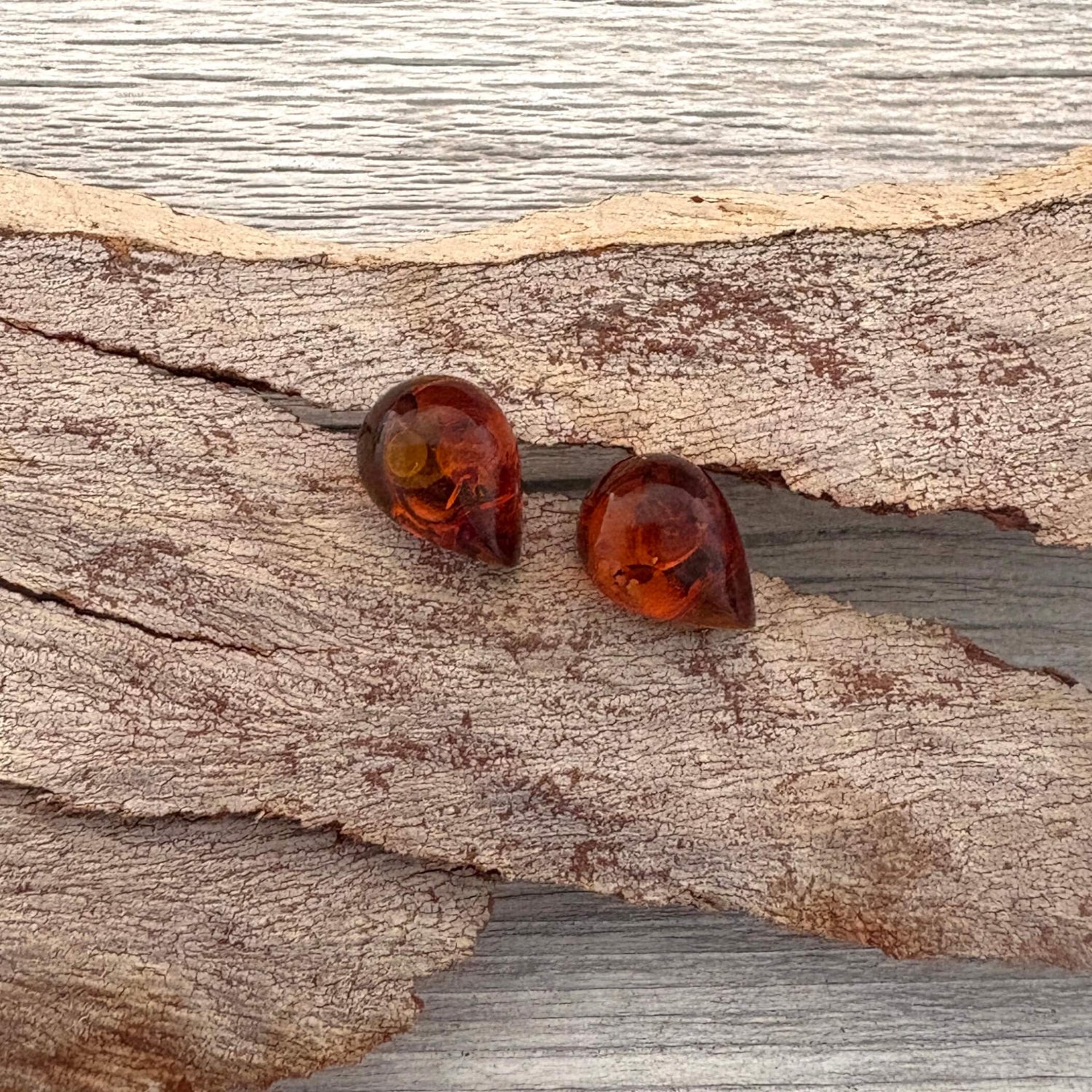 Pair of amber cognac colored earrings on a wooden surface