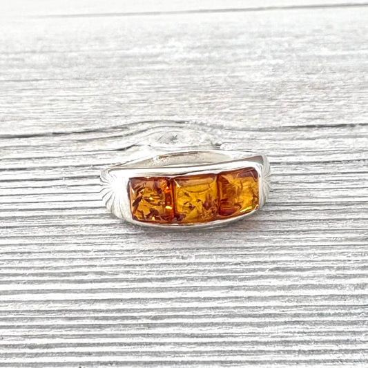 Silver ring with amber stones on a wooden surface