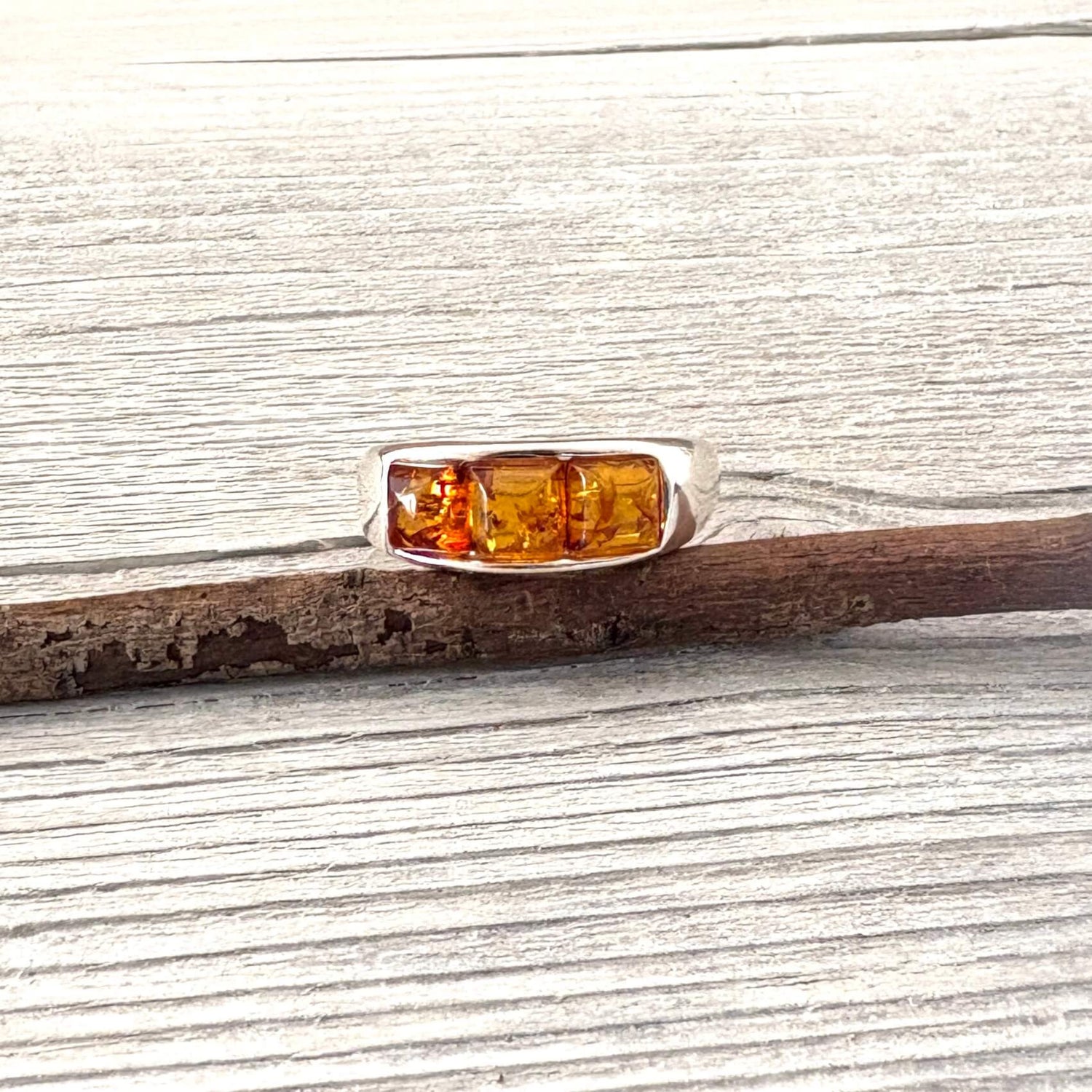 Silver ring with amber stones on a wooden surface