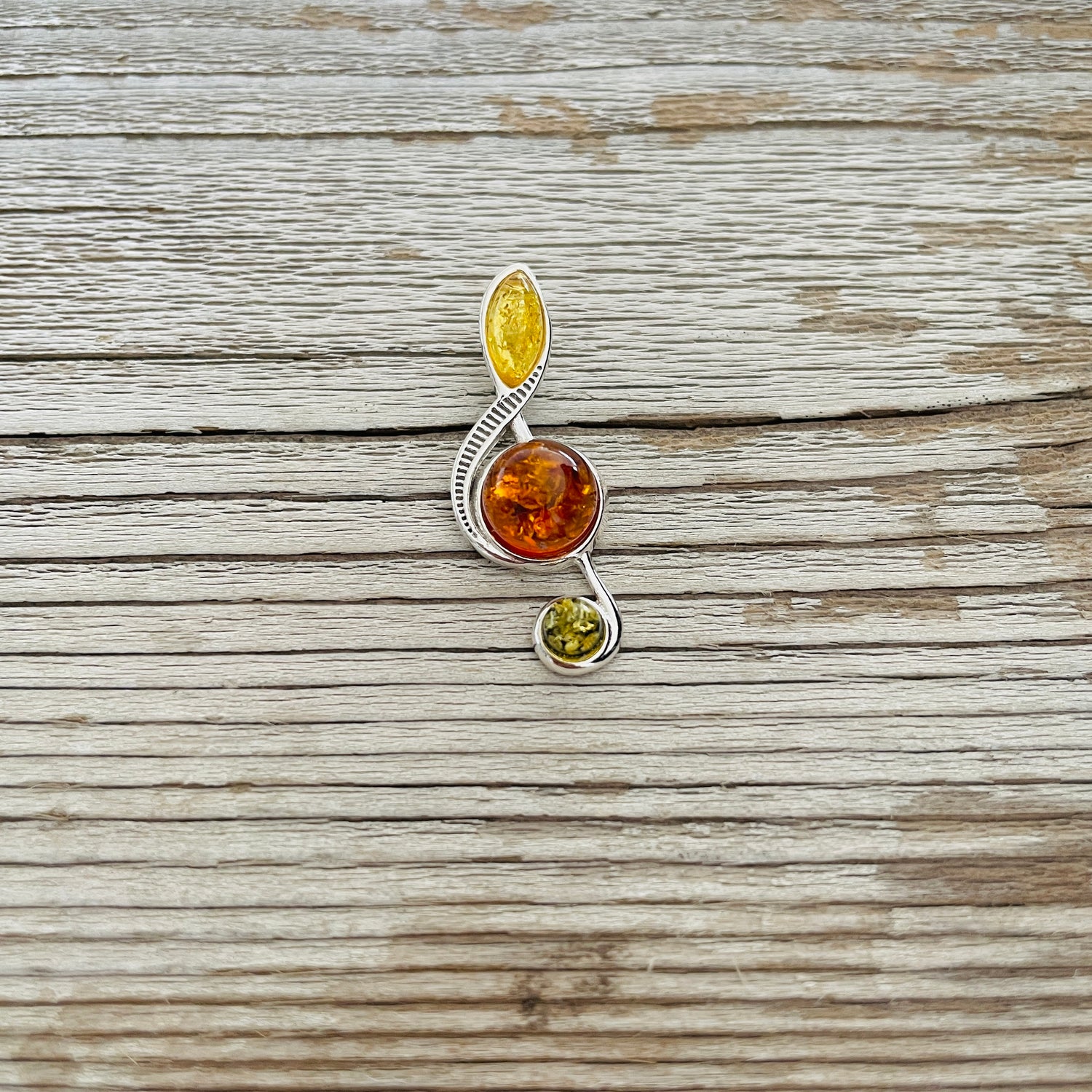 yellow cognac amber set in treble clef shaped sterling silver pendant