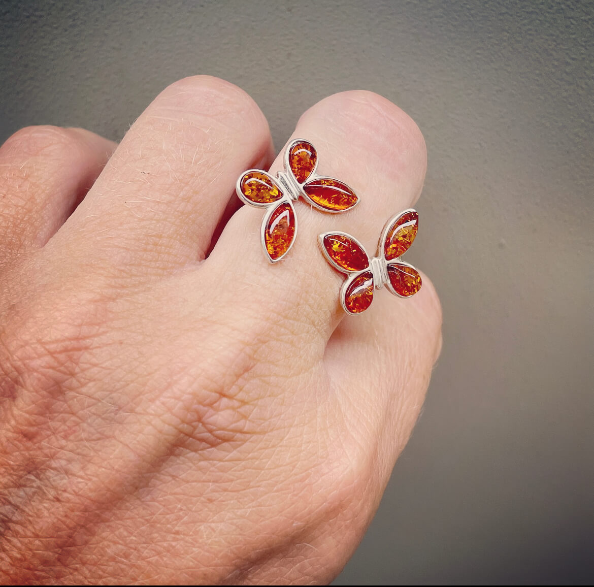 butterfly shaped adjustable cognac coloured amber ring on a finger